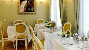 Un comedor con mesas dispuestas para el servicio, un retrato enmarcado en la pared y cortinas en las ventanas.