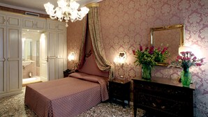 Un dormitorio con una cama grande, un aparador, un espejo y una araña.