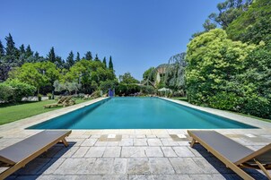 Piscina retangular com superfície de água azul translúcida, ladeada por um deck de pedra.