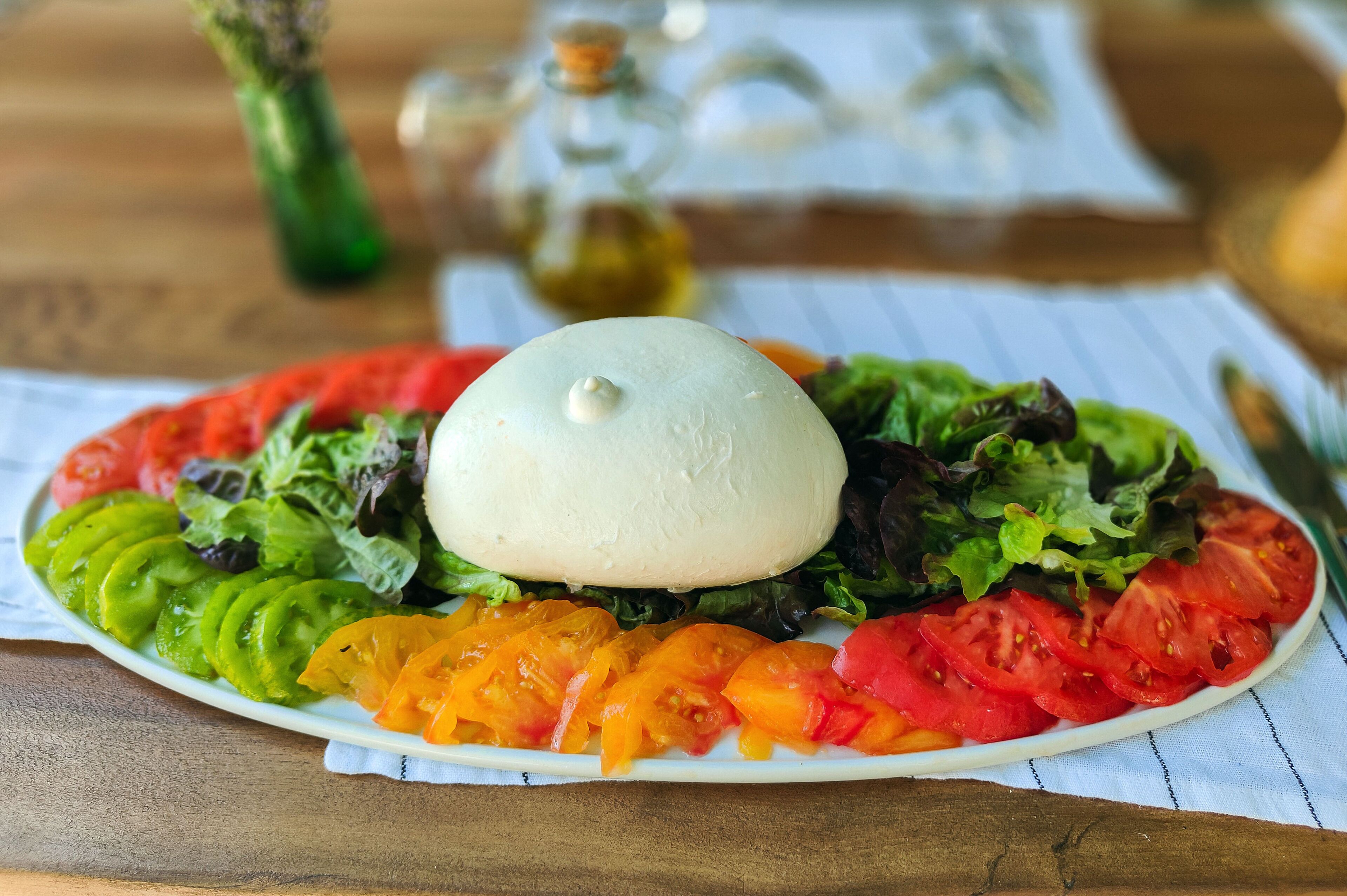 A plate of food with a variety of vegetables and a white dome-shaped item on top.