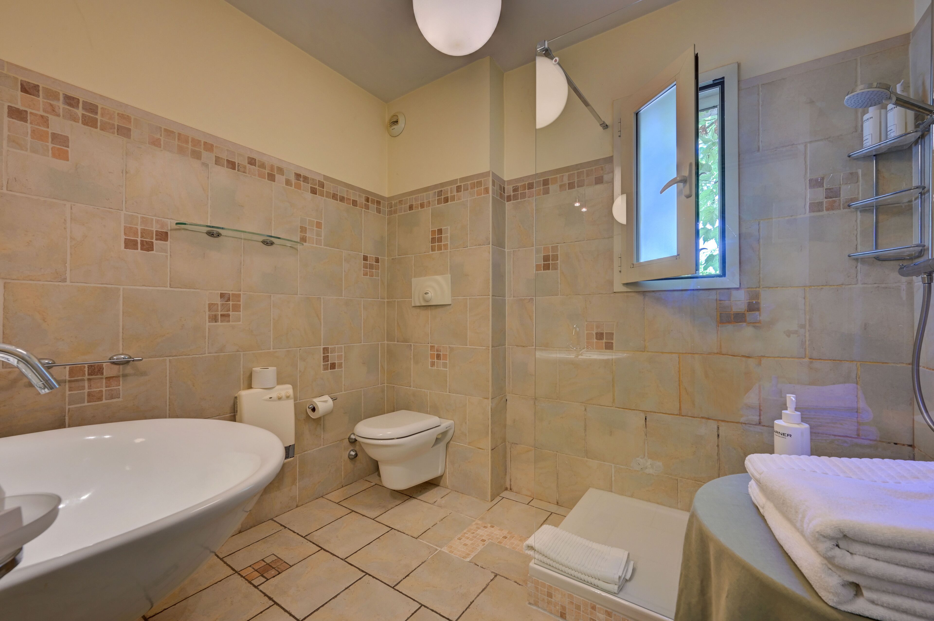 Un baño con una bañera grande, inodoro y zona de ducha.