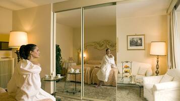 Una habitación con una cama, un área de descanso con una mesa y sillas, un espejo y una lámpara.