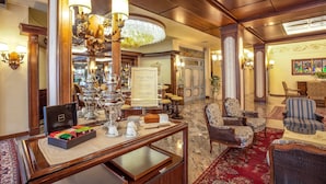 Un lobby de hotel lujoso con una gran lámpara de araña, muebles elegantes y un bufé de desayuno.