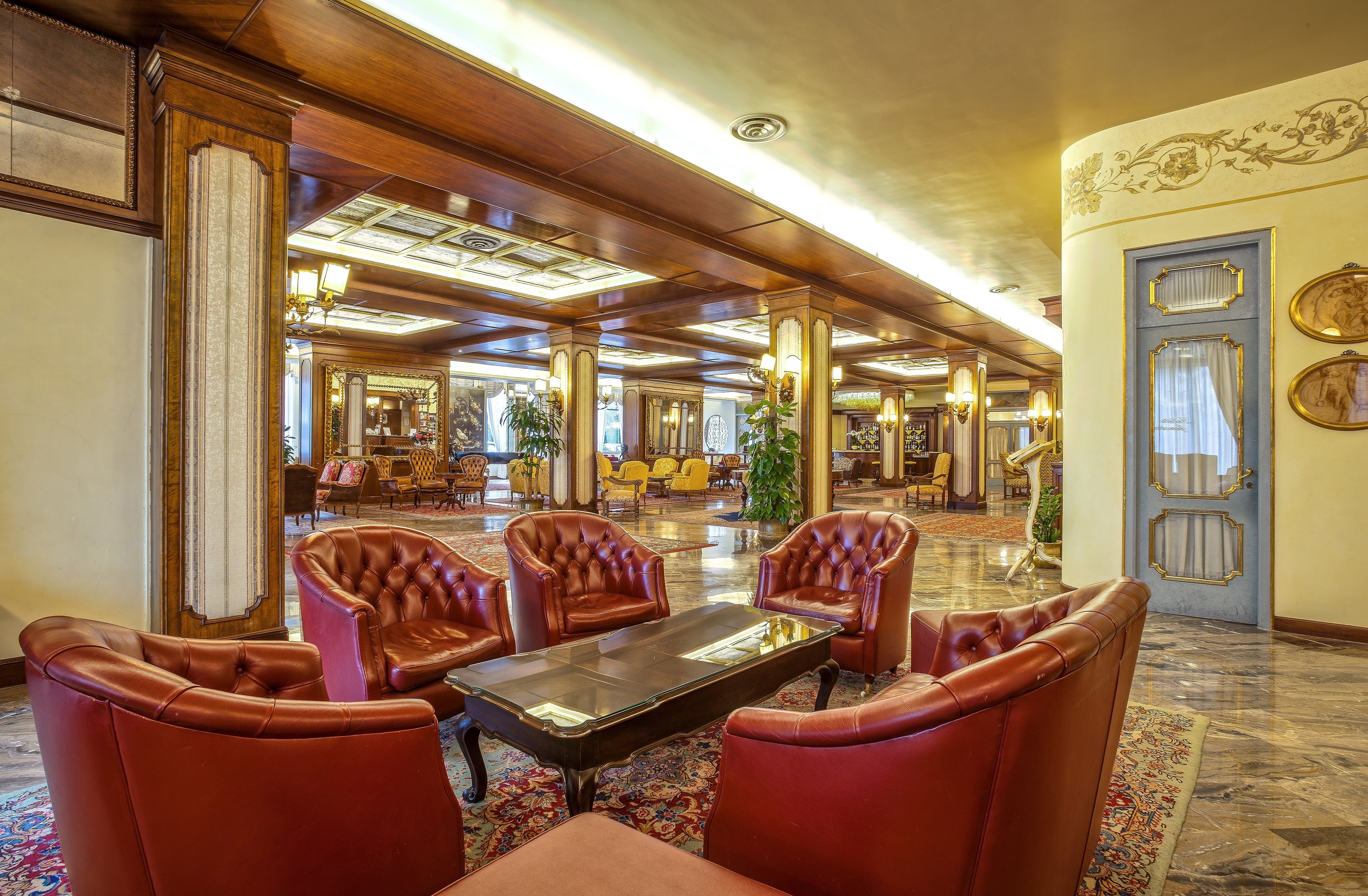 A spacious lobby with leather armchairs, a central coffee table, and a grand mirror.