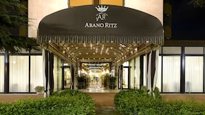 La entrada del hotel Abano Ritz, con un corredor cubierto y plantas en macetas.