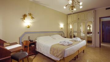 Una camera d'albergo con un letto, una scrivania, una sedia, un armadio e un lampadario.