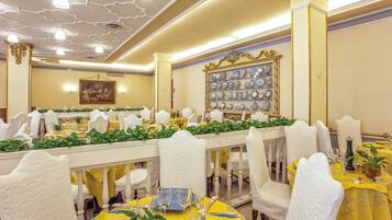 Un comedor formal con sillas blancas, manteles amarillos y una pared decorada con platos.