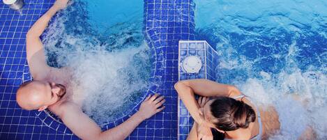 A swimming pool with a tiled floor and a water fountain feature.