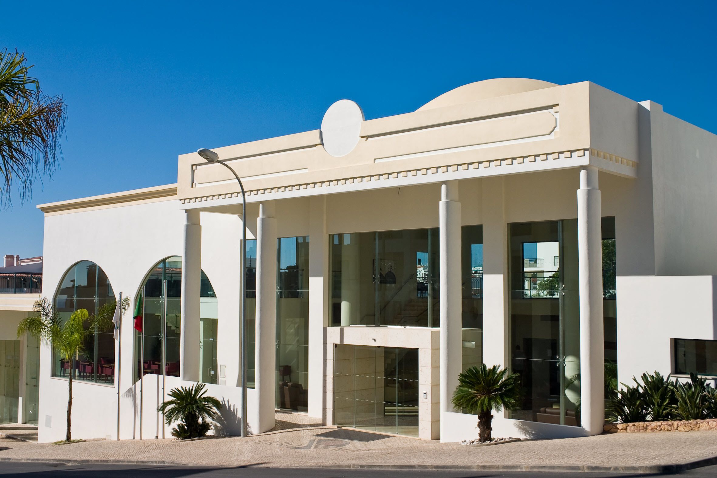 A modern building with large glass windows, a flat roof, and a central entrance with a decorative element.