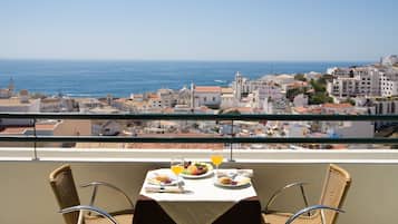 Un balcone con tavolo apparecchiato per la colazione, vista sulla città costiera.