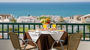 A table set for breakfast with a view of the sea, wicker chairs, and a balcony railing. - Cerro Mar Atlantico & Cerro Mar Garden (Albufeira)