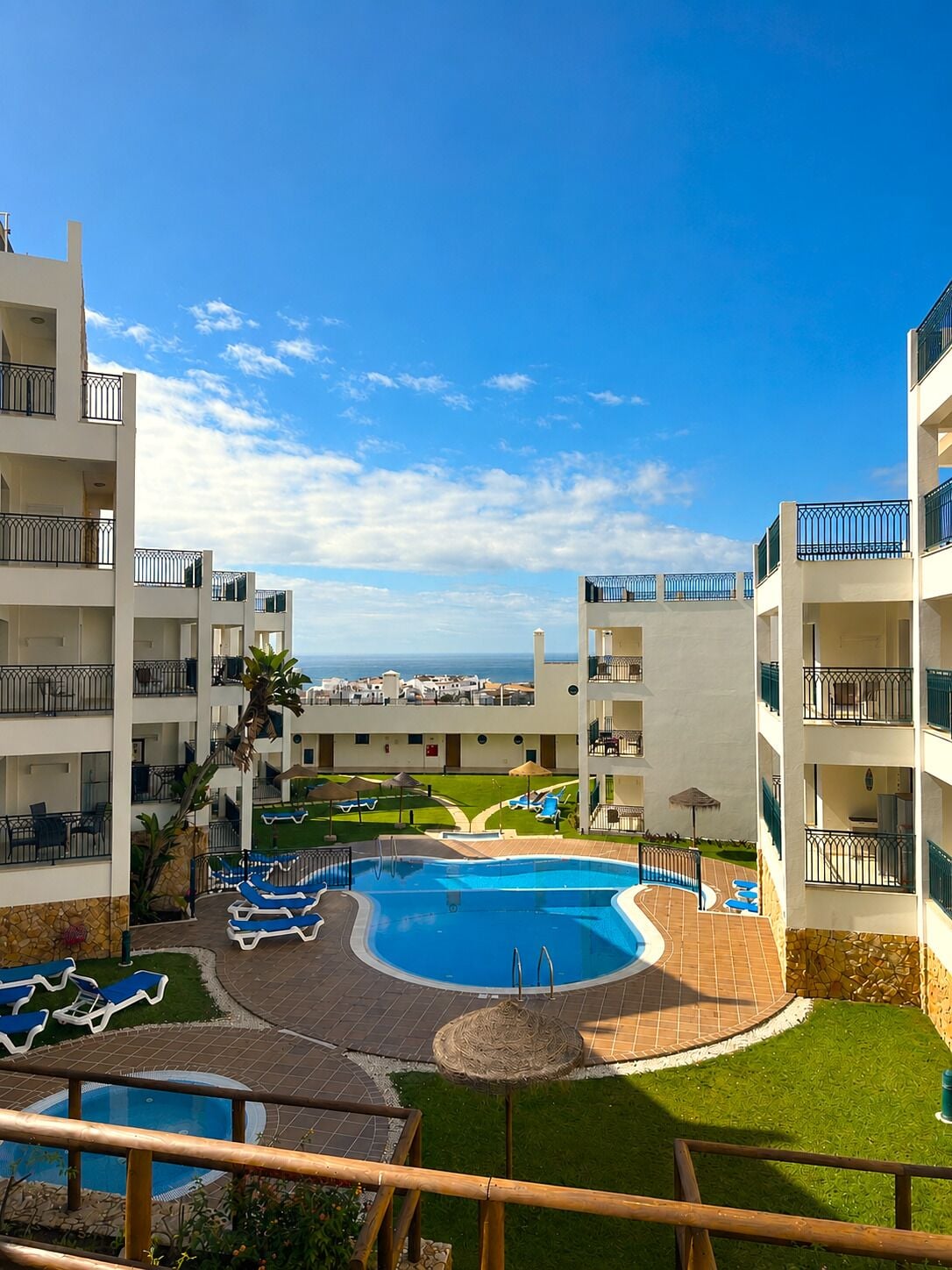 Een resort met meerdere balkons, een centraal gelegen zwembad en uitzicht op de oceaan.