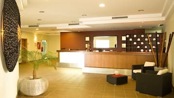 A lobby with a reception desk, seating area, and a large decorative wall piece.