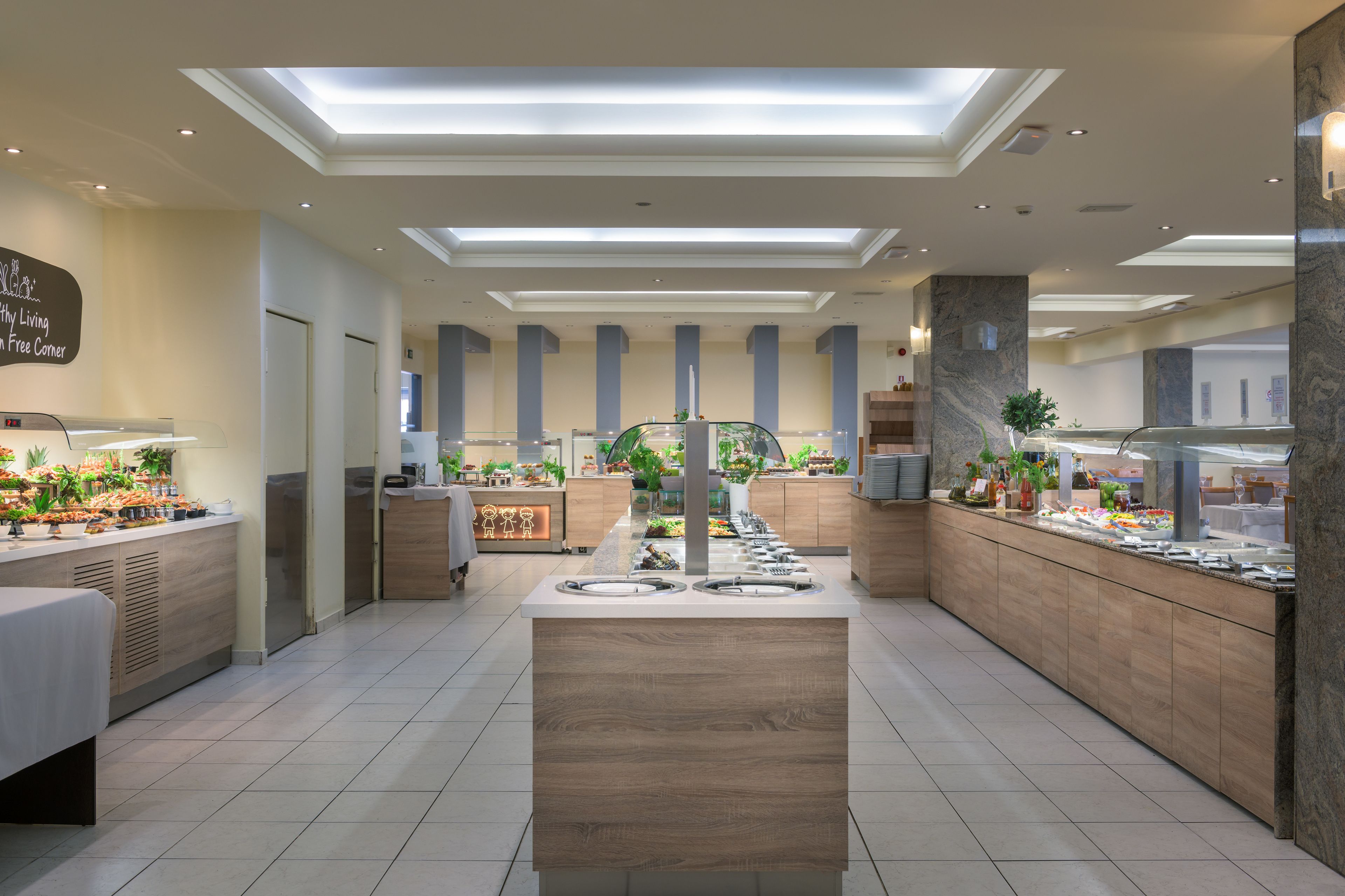 A modern hotel lobby with a central island, a reception desk, and a buffet area.