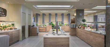 A modern hotel lobby with a central island, a reception desk, and a buffet area.