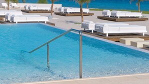 Un espace piscine avec des chaises longues et une vue sur l’océan.