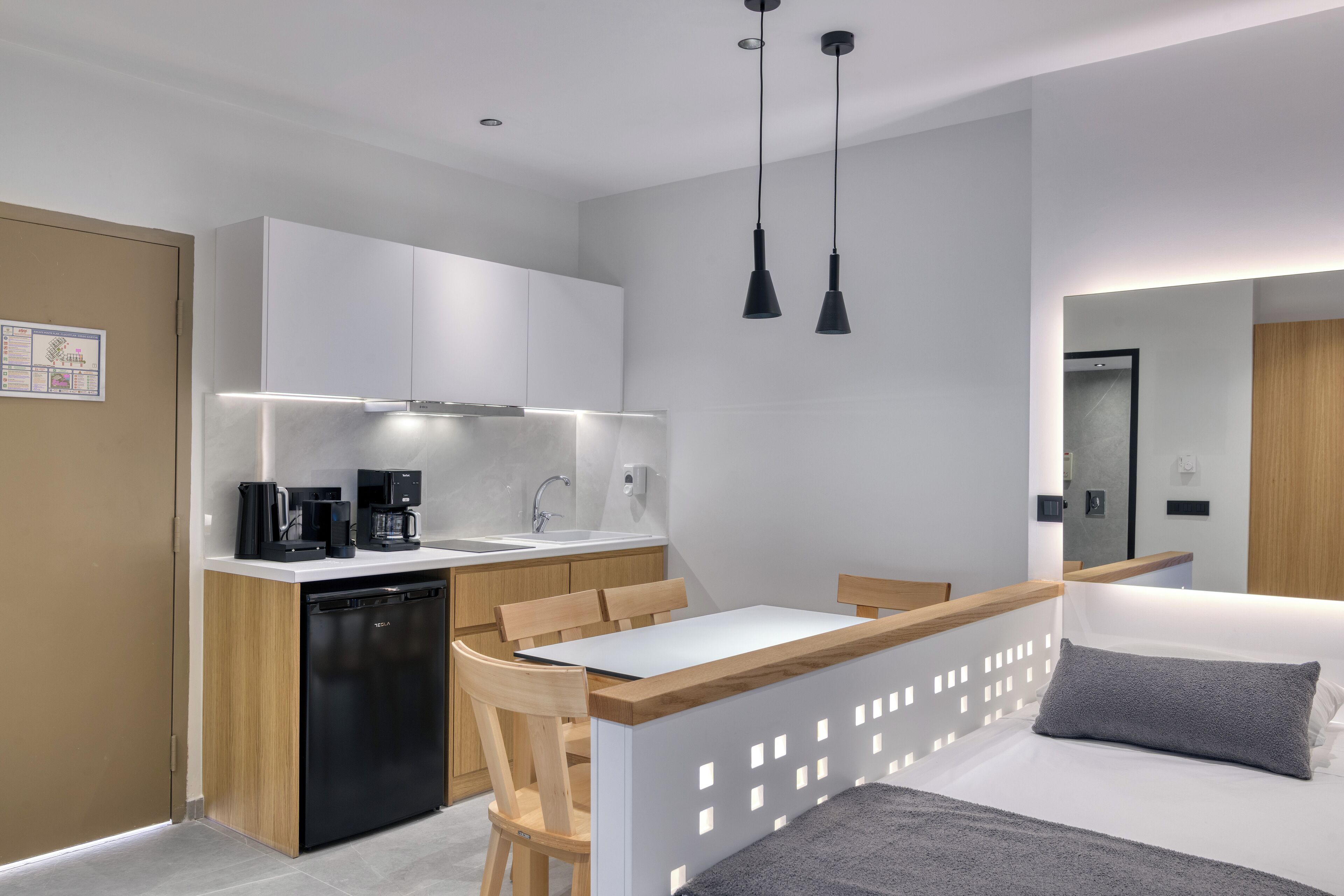 A compact kitchen with a dishwasher, coffee maker, and a dining area with a wooden table and chairs.