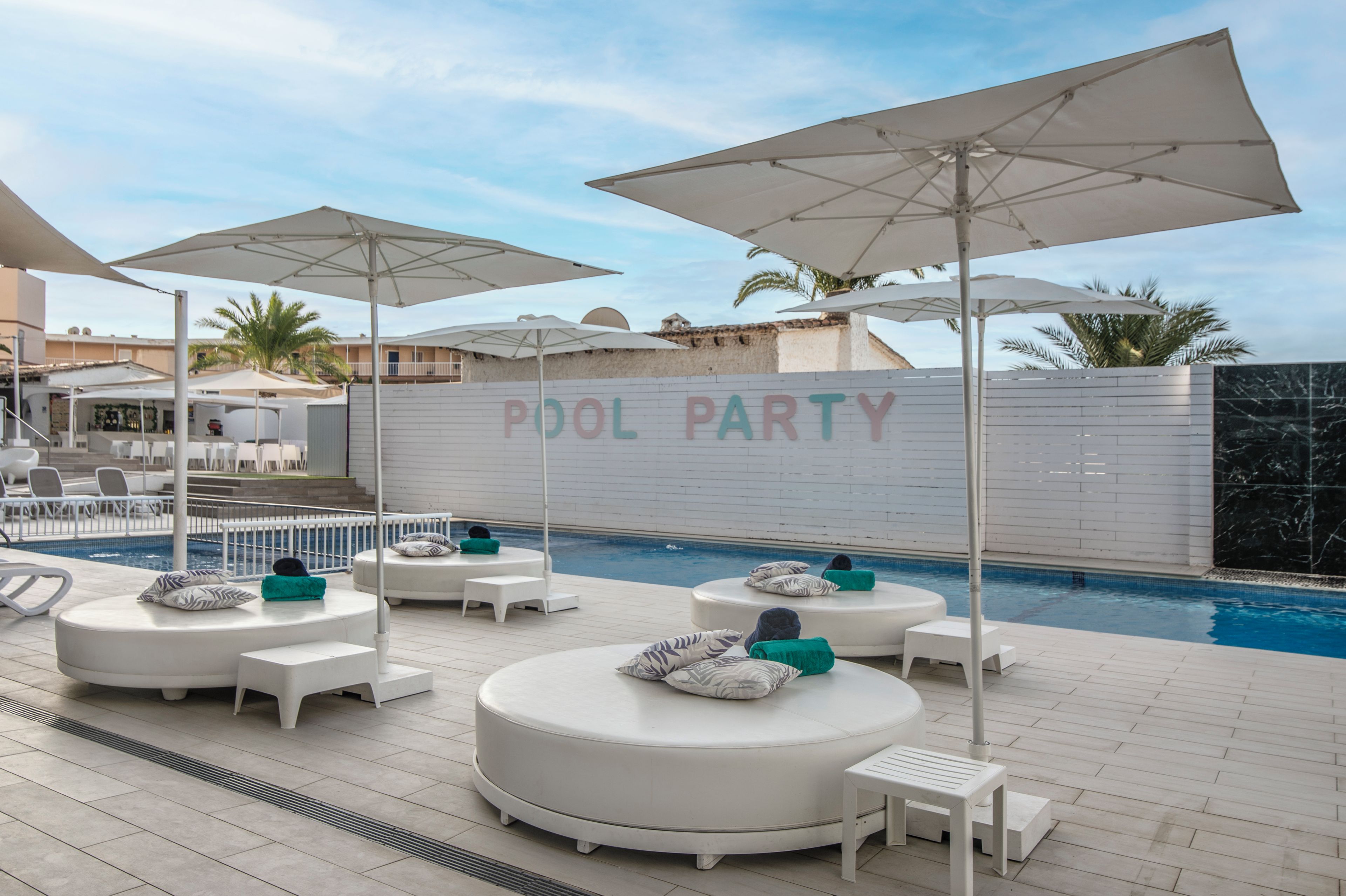 A poolside area with lounge chairs and umbrellas, a pool, and a 'POOL PARTY' sign.
