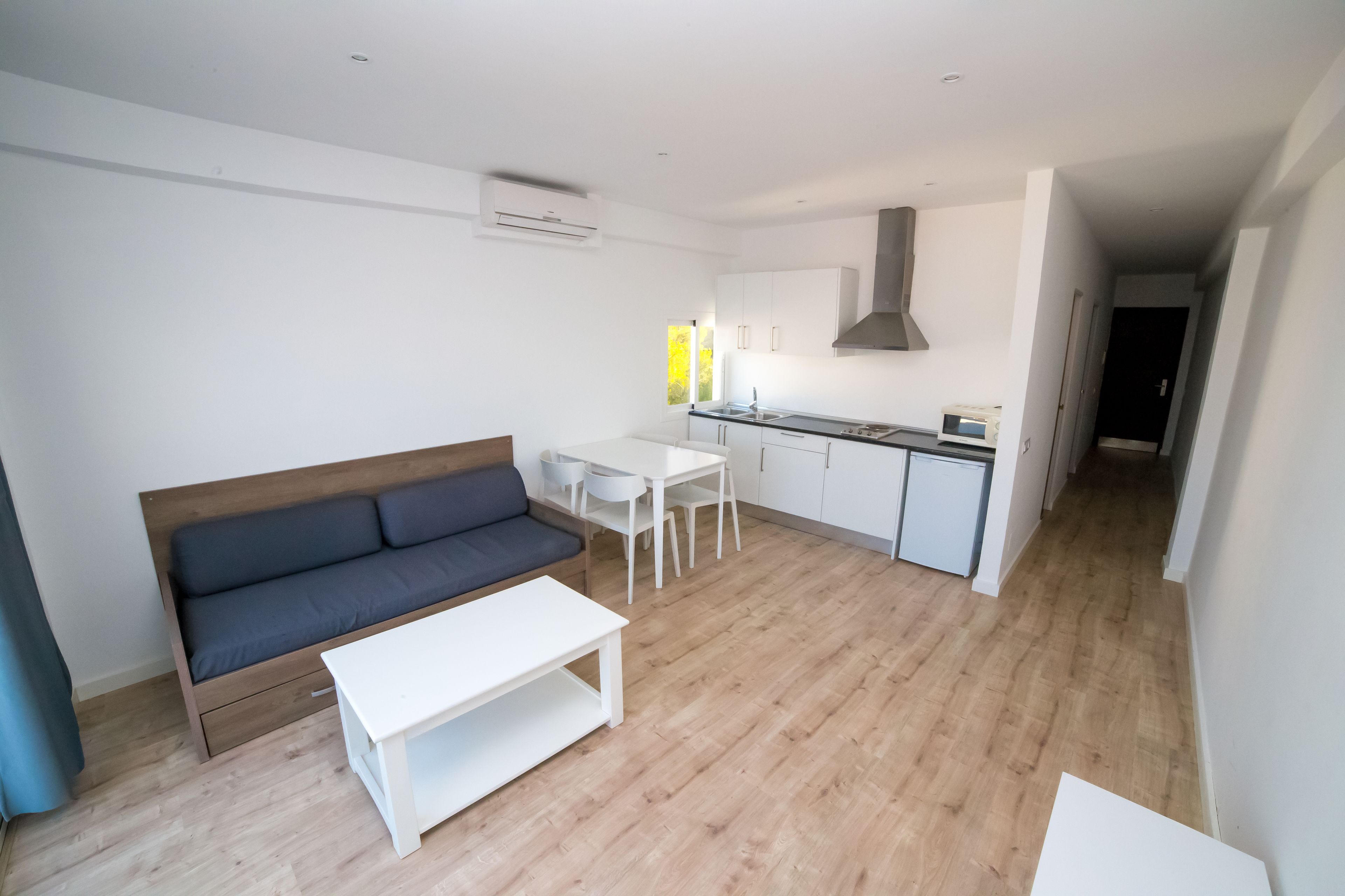 A modern living room with a sofa, a coffee table, and a dining area with a table and chairs.