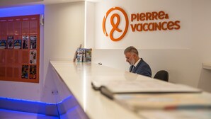 Una recepción con un cartel que dice "Pierre & Vacances" y una pared iluminada en azul con un tablón de anuncios.