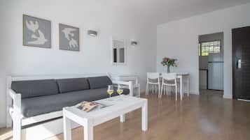 Una sala moderna con un sofá gris, una mesita de centro blanca y dos copas de vino.