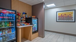 Un área de venta con Coca-Cola y otras bebidas, un refrigerador y aperitivos.