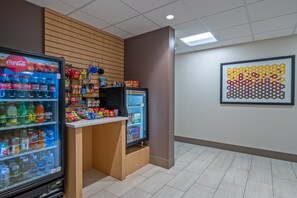 A vending area with Coca-Cola and other beverages, a refrigerator, and snacks. - Holiday Inn Express Hotel & Suites Woodbridge by IHG (Woodbridge)
