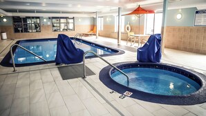 An indoor swimming pool area with two pools, a lounge area, and a caution sign on the wall. - Holiday Inn Express Hotel & Suites Douglas by IHG (Douglas)