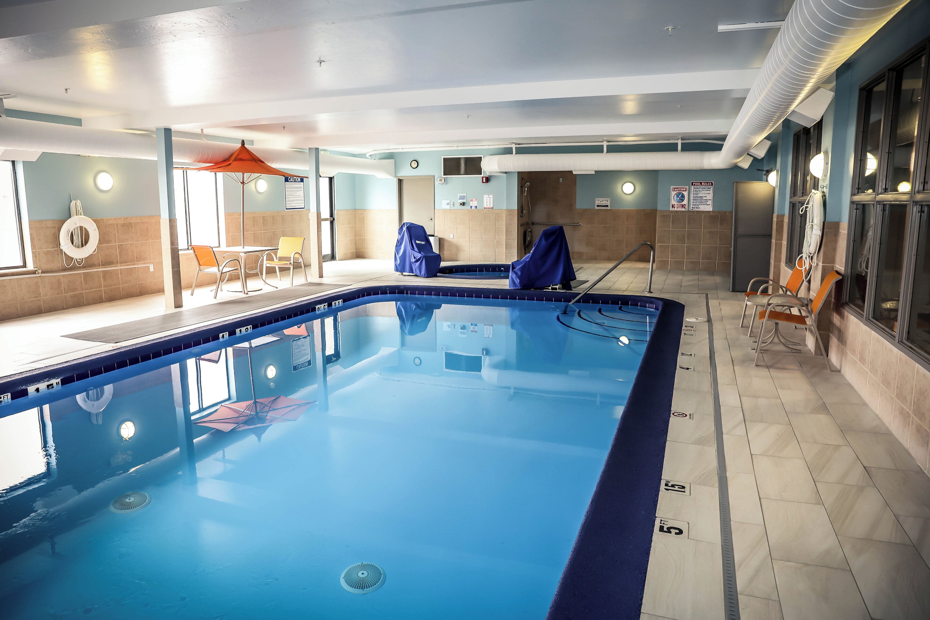 An indoor swimming pool with clear lane markings, a covered changing area, and safety equipment.