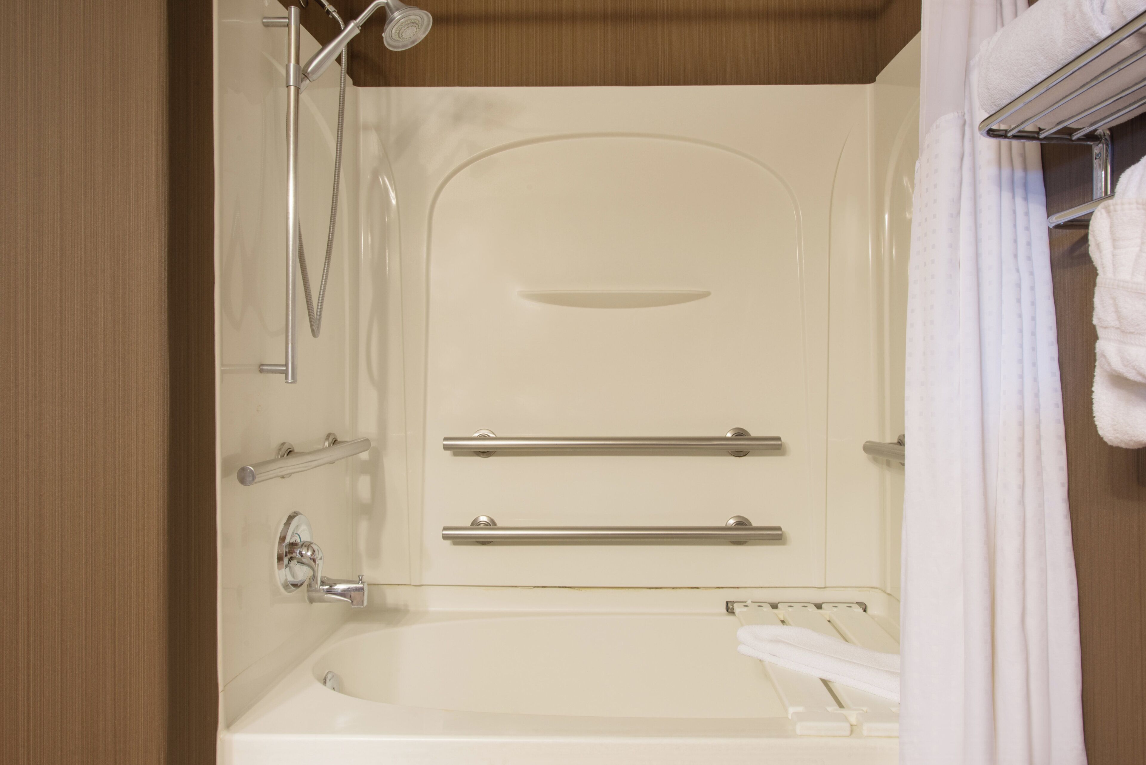 A modern bathroom with a bathtub, a shower, and a towel rack.