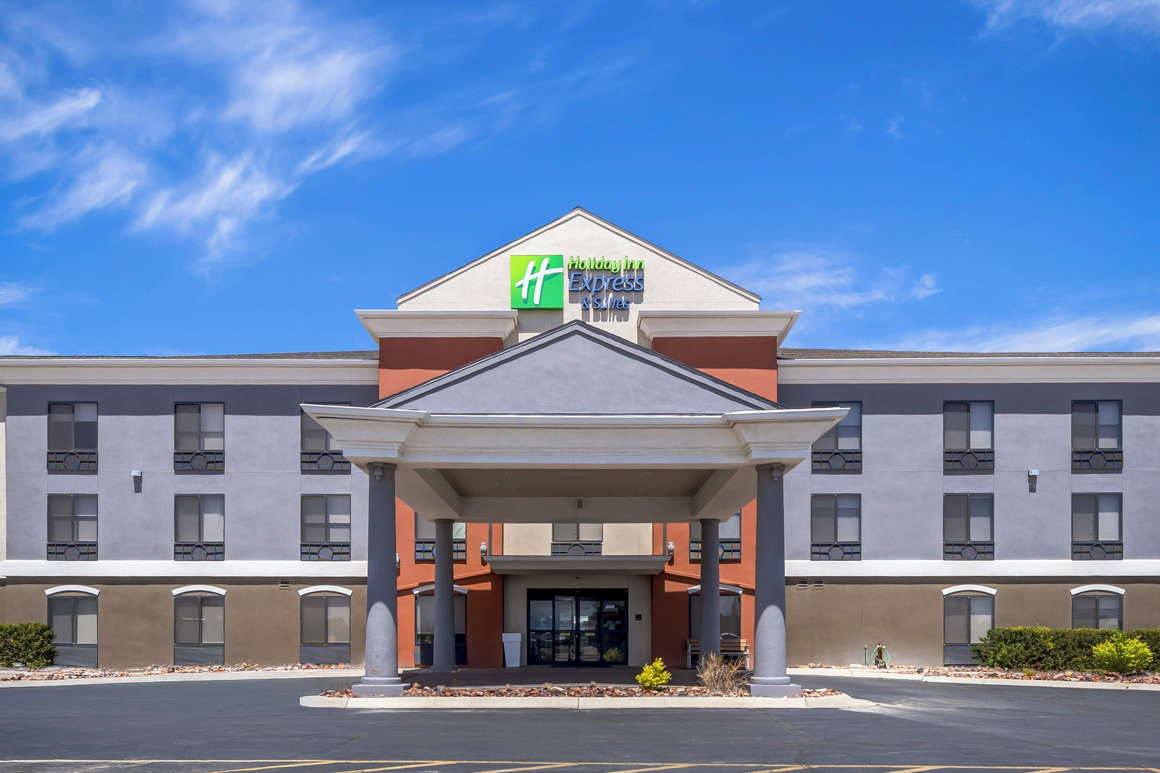 Ein Holiday Inn Express & Suites Hotel mit überdachter Einfahrt und blauem Himmel.