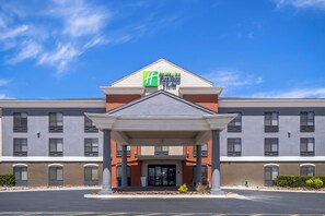 A Holiday Inn Express & Suites hotel with a covered entrance and a clear blue sky.