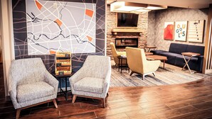 A lobby with two armchairs, a wooden floor, a fireplace, and a wall with a map and artwork. - Holiday Inn Express Hotel & Suites Douglas by IHG (Douglas)
