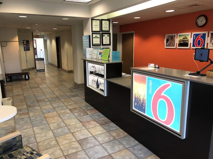A reception area with a counter displaying the number 6, framed certificates on the wall, and a clock above the counter.