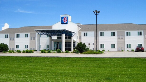 A motel with a covered entrance, multiple windows, and a parking area. - Motel 6 Avoca, IA (Avoca)