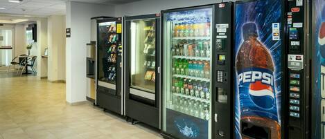 Una hilera de máquinas expendedoras en un pasillo, incluyendo una máquina de Pepsi.