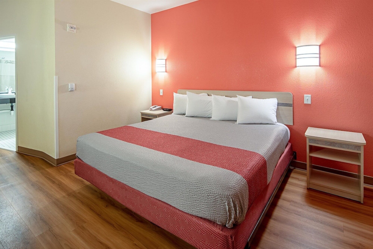 A hotel room with a bed, bedside tables, and a nightstand.