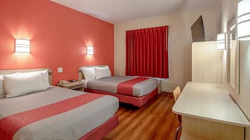 A hotel room with two beds, a desk, and a TV.