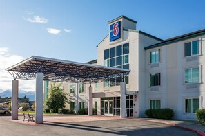 A Motel 6 building with a covered entrance, large windows, and a prominent 'Motel 6' sign. - Motel 6 Anchorage, AK - Midtown (Anchorage)
