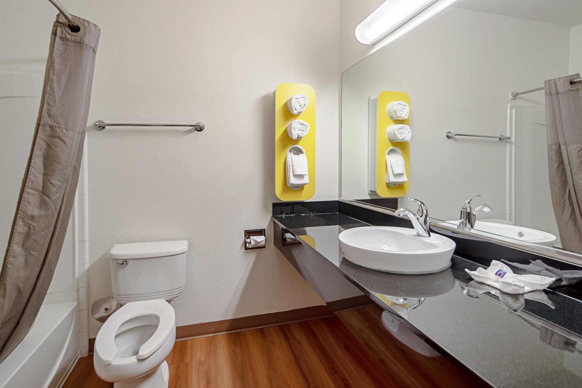 A modern bathroom with a toilet, sink, and mirror.