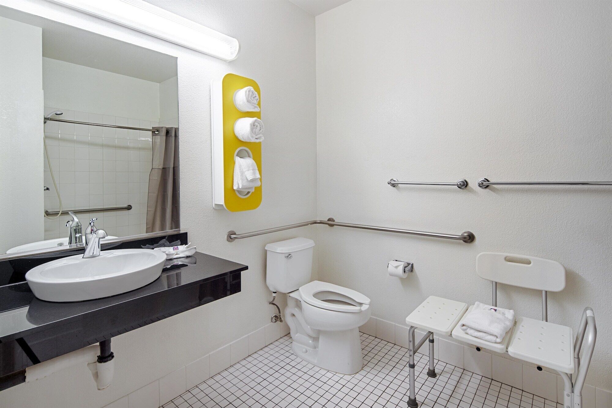 A modern bathroom with a sink, toilet, and handrails.