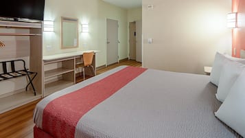 A hotel room with a bed, a desk with a chair, a TV, and a wardrobe.