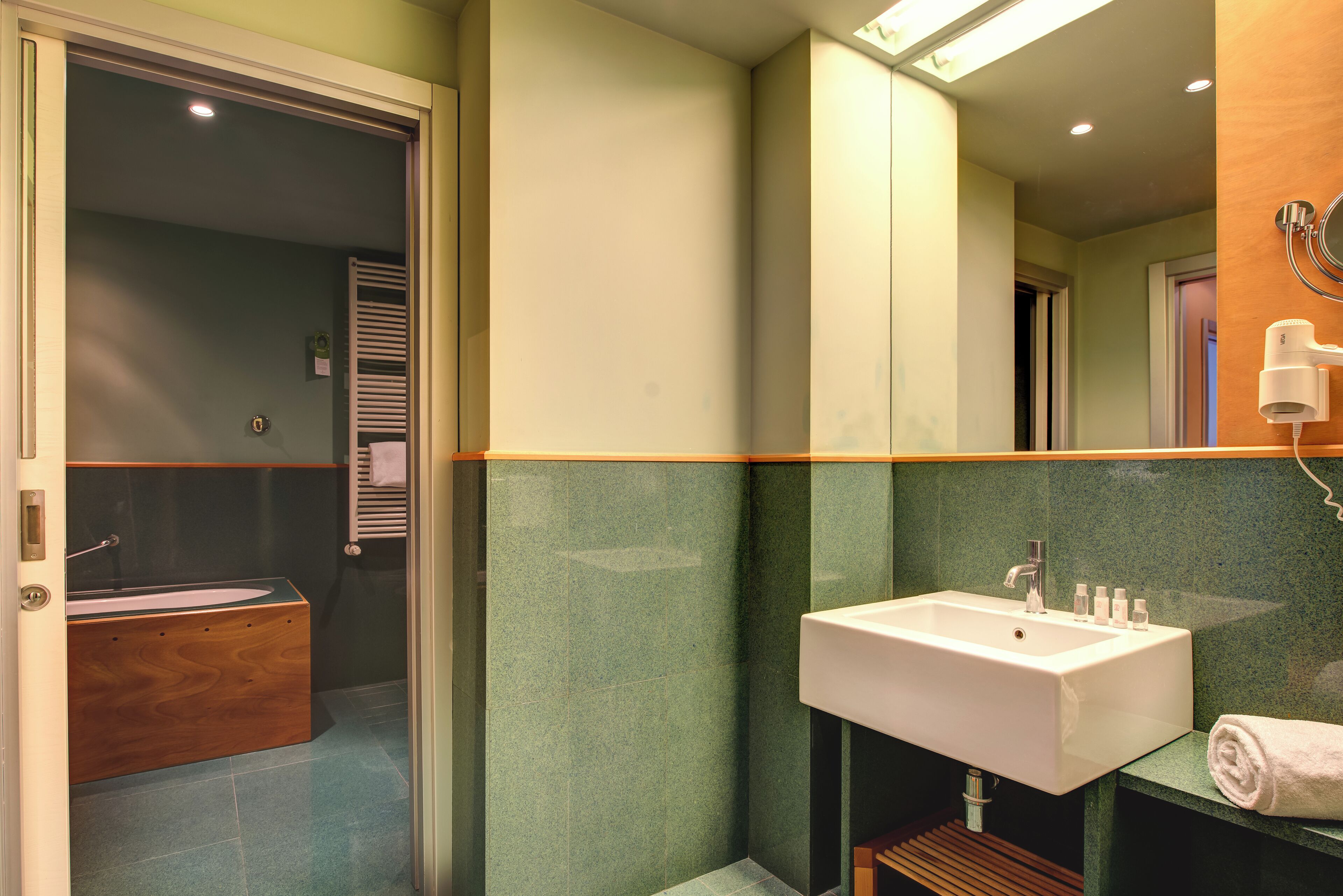 Un baño con una bañera de madera, un lavamanos blanco y un espejo.