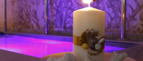 A candle with a lit flame on a table, surrounded by decorative elements.