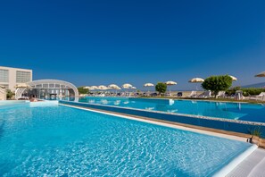 A large outdoor swimming pool with lounge chairs and umbrellas, surrounded by buildings and a clear sky. - Towers Hotel Stabiae Sorrento Coast (Castellammare di Stabia)