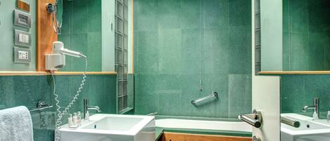 Un baño moderno con una bañera grande, zona de ducha y tocador con espejo.