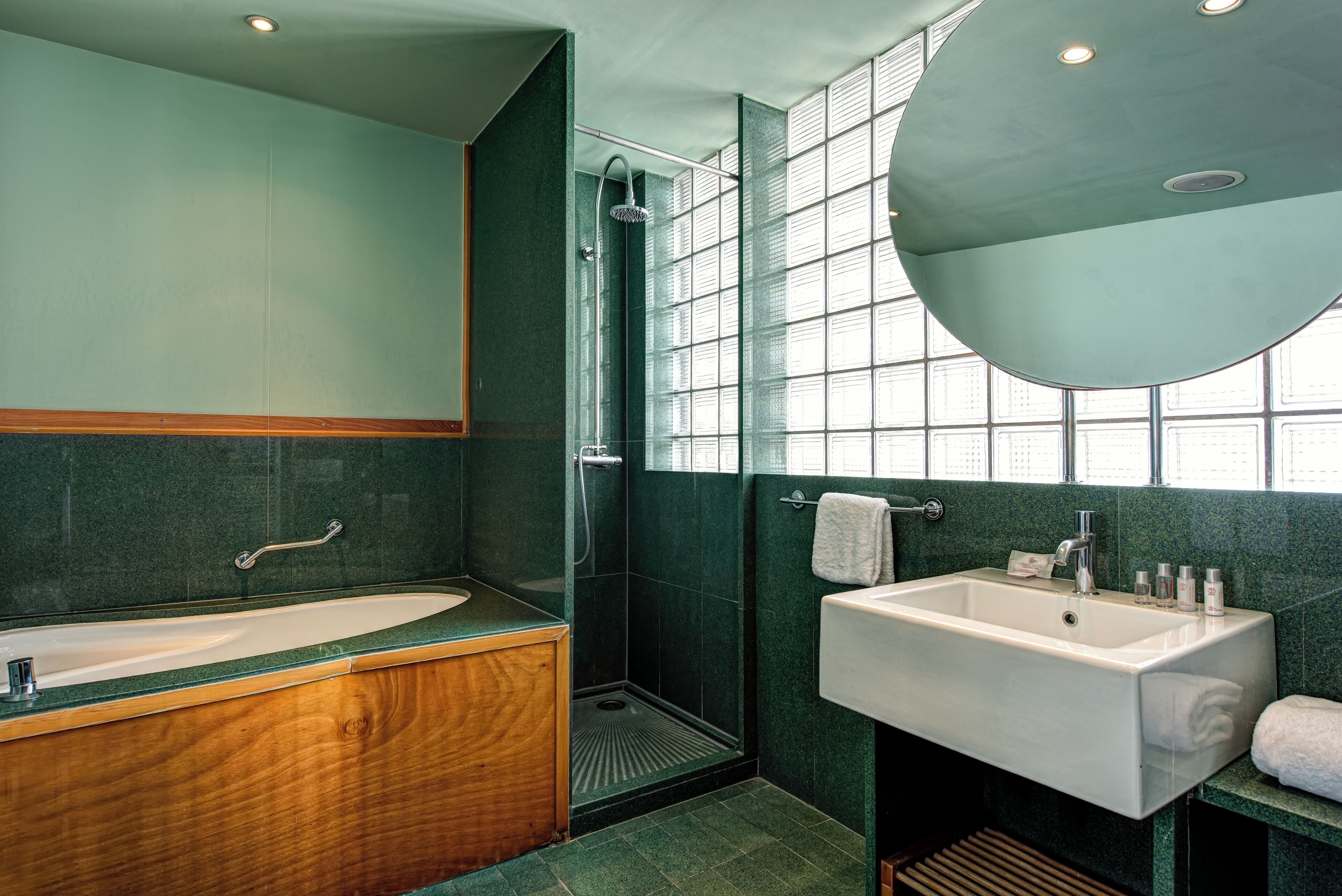 A bathroom with a wooden vanity, a white sink, a shower, and a large mirror.