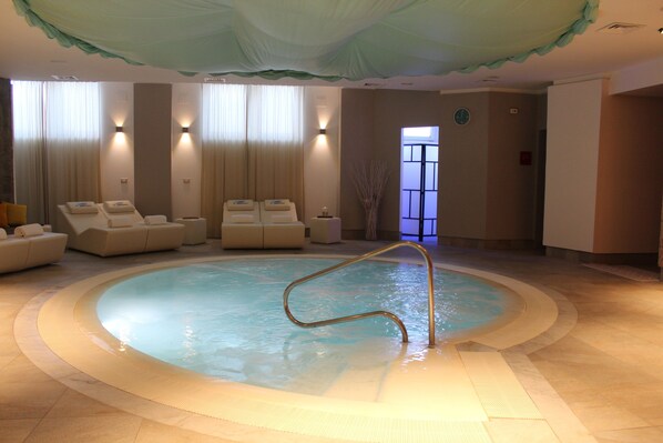A spa area with a hot tub, seating, and a large window.