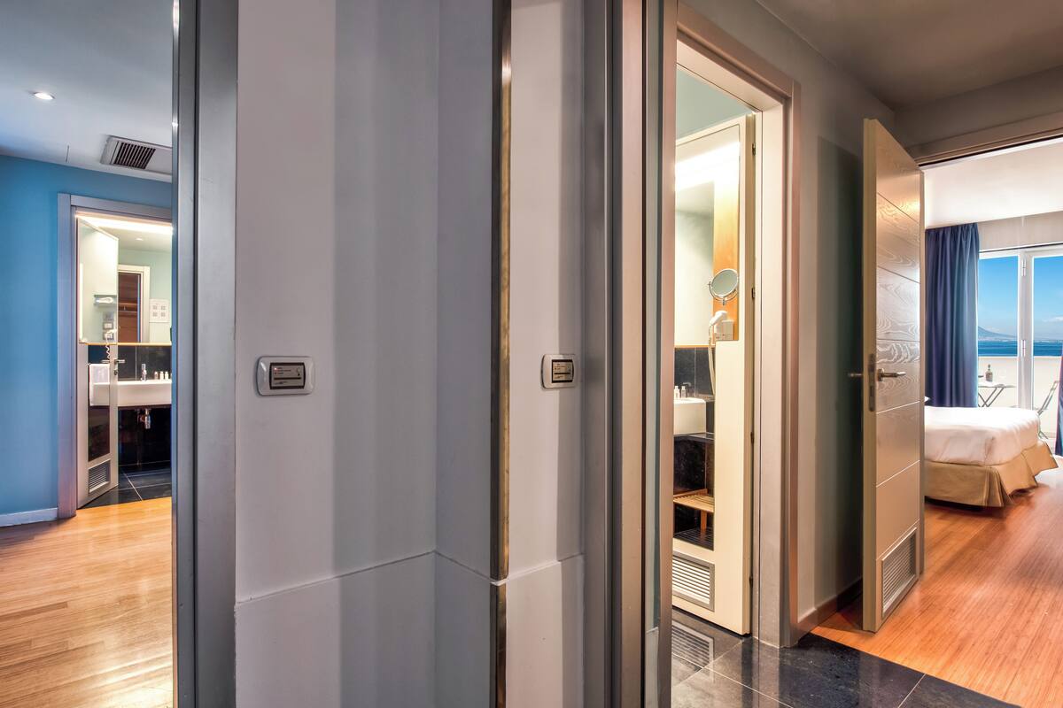 Ein modernes Hotelzimmer mit großem Spiegel, einem Bett und Meerblick.
