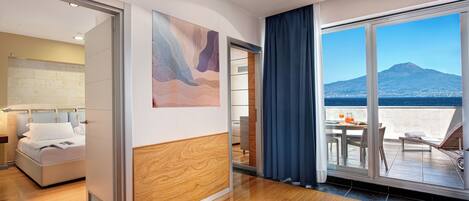 Una habitación de hotel moderna con suelo de madera, cama, baño y balcón con vistas a la montaña.